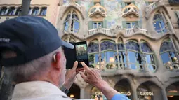 Seorang turis mengambil gambar dengan ponselnya di Casa Batllo karya arsitek Catalan Antoni Gaudi di Barcelona, ​​pada 11 Mei 2022. Pengunjung sekali lagi memadati jalan-jalan sempit di kawasan Gothic Barcelona yang sempit saat perjalanan global bangkit kembali dari pandemi COVID-19, menghidupkan kembali kekhawatiran atas pariwisata massal di kota pelabuhan Spanyol. (LLUIS GEN / AFP)