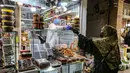 Pedagang mengenakan masker dan sarung tangan melayani pembeli di pasar Tajrish selama bulan suci Ramadan di Taheran, Iran (25/4/2020). Di pasar ini pedagang dan pembeli beraktivitas mengenakan alat pelindung seperti masker dan sarung tangan akibat pandemi coronavirus COVID-19. (AFP/Atta Kenare)