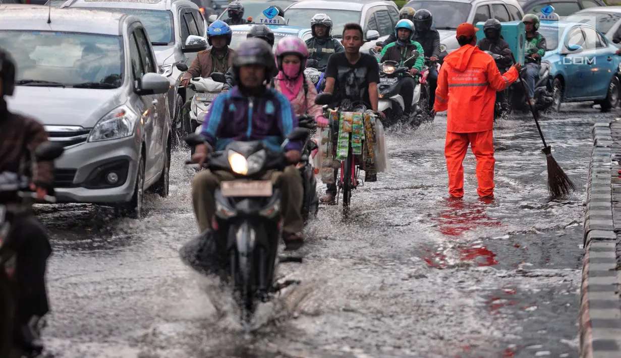 Sejumlah kendaraan melintasi genangan air usai hujan deras dikawasan Tugu Tani, Jakarta, Kamis (12/10). Agar tidak terjadi genangan kembali petugas dari Dinas Kebersihan membuang aliran air hujan kedalam selokan. (Liputan6.com/Faizal Fanani)