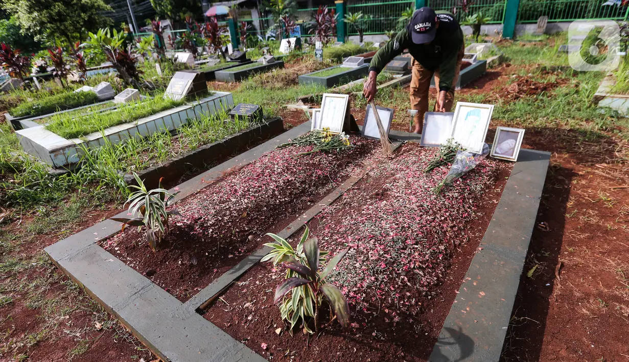 Pengurus makam membersihkan makam Vanessa Angel dan Bibi Ardiansyah di TPU Taman Makam Islam Malaka Blok D, Pesanggrahan, Jakarta, Senin (7/02/2022). Pada Perda Jakarta No.3/2007 Pasal 26 pemindahan dan penggalian jenazah sebaiknya dilakukan satu tahun setelah dimakamkan. (Liputan6.com/Fery Pradolo)