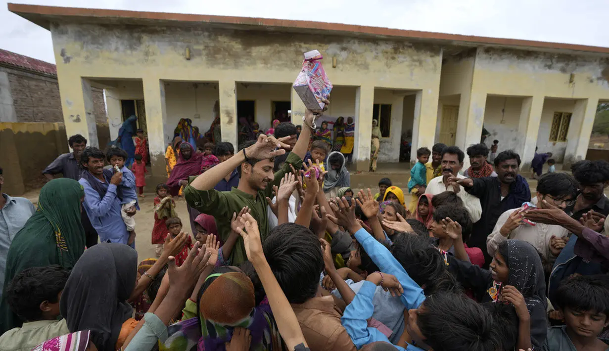 <p>Seorang sukarelawan membagikan makanan kepada anak-anak di sebuah kamp yang didirikan di gedung sekolah untuk para pengungsi internal dari daerah pesisir saat Topan Biparjoy mendekat di Badin, Provinsi Sindh, Pakistan, Kamis (15/6/2023). India dan Pakistan yang menderita banjir mematikan tahun lalu bersiap untuk banjir baru saat Topan Biparjoy mendekat dengan cepat. (AP Photo/Fareed Khan)</p>