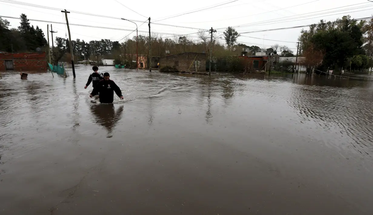 Warga berjalan ditengah – tengah banjir yang melanda daerah Lujan, Argentina, Rabu (12/8/2015). Hujan lebat selama berhari – hari menyebabkan tebing sungai utama pecah termasuk di daerah Lujan, Areco dan Arrecifes. (REUTERS/Marcos Brindicci)