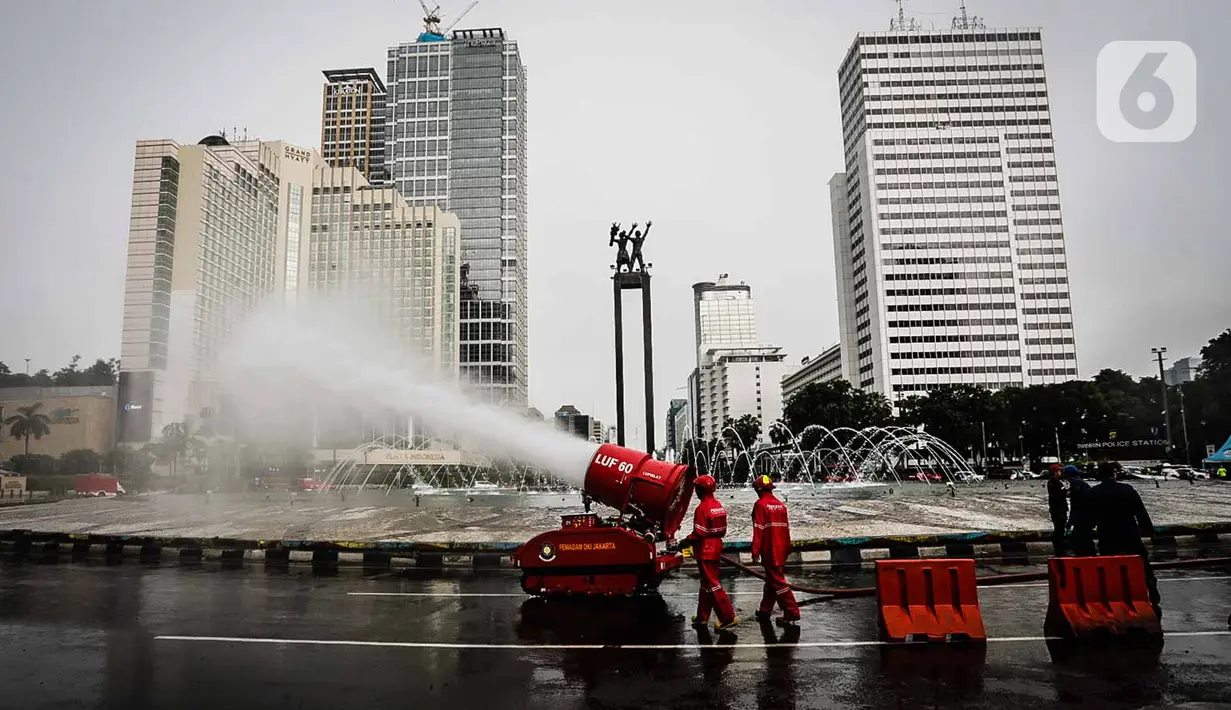 Petugas pemadam kebakaran menyemprotkan cairan disinfektan menggunakan robot LUF 60 di kawasan Bundaran HI, Jakarta, Minggu (22/3/2020). Pemprov DKI Jakarta melakukan penyemprotan fasilitas umum untuk mencegah penyebaran virus corona COVID-19. (Liputan6.com/Faizal Fanani)
