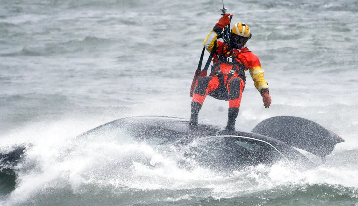 Penyelam Penjaga Pantai AS diturunkan dari helikopter untuk menarik tubuh pengendara mobil yang terjebak dalam arus deras di tepi Air Terjun Niagara, New York, AS, 8 Desember 2021. Masih belum jelas apakah pengemudi masuk ke sungai dengan sengaja atau tidak. (AP Photo/ Jeffrey T. Barnes)