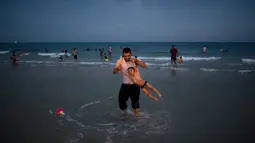 Warga Palestina dan putranya bermain di pantai selama libur Idul Fitri di Tel Aviv, Israel, Sabtu (16/6). (AP Photo/Oded Balilty)