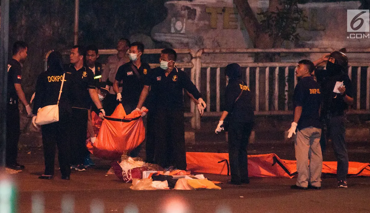 Polisi dan Puslabfor mengevakuasi potongan jenazah ketika  olah TKP ledakan di Terminal Kampung Melayu, Rabu (24/5). Selain memotret dan menyusuri lokasi, petugas juga berjaga di lokasi ledakan. (Liputan6.com/Yoppy Renato)
