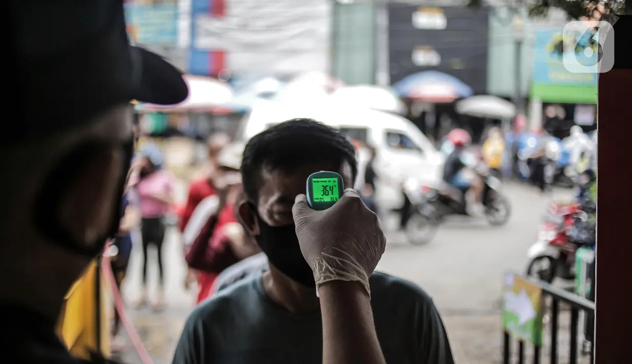 Petugas mengecek suhu tubuh pengunjung Pasar Kebayoran Lama, Jakarta Selatan, Senin (22/6/2020). Pasar Kebayoran Lama menerapkan protokol kesehatan bagi pengunjung dan pedagang untuk mengantisipasi penularan COVID-19. (Liputan6.com/Faizal Fanani)