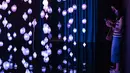 Orang-orang mengunjungi "Pixel Forest" oleh seniman Swiss Pipilotti Rist, sebuah instalasi seni dari 3000 lampu LED pahatan tangan yang digantung di langit-langit di Tai Kwun di Hong Kong (18/8/2022). (AFP/Isaac Lawrence)