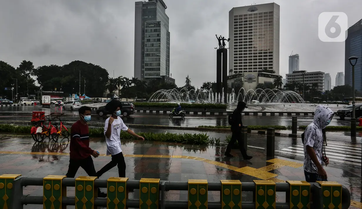 Pejalan kaki melintasi trotoar saat hujan di kawasan Jakarta, Selasa (16/2/2021). Setelah memulai vaksinasi COVID-19 tahap pertama dengan sasaran petugas kesehatan, kini pemerintah menargetkan lansia dan petugas pelayanan publik untuk penerima vaksinasi tahap kedua. (Liputan6.com/Johan Tallo)