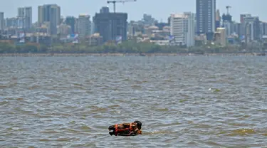 Seorang penjaga membawa kudanya untuk berendam di laut pada suatu hari di musim panas di Mumbai pada tanggal 8 Mei 2024. (Punit PARANJPE/AFP)