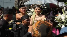 Pasangan pengantin Kaesang Pangarep dan Erina Gudono menaiki kereta saat prosesi kirab Ngunduh Mantu di kawasan Selamet Riyadi, Solo, Jawa Tengah, Minggu (11/12/2022). Kirab ngunduh mantu pernikahan putra bungsu Presiden Joko Widodo, Kaesang Pangarep dan istrinya Erina Gudono yang dimulai dari Loji Gandrung menuju Pura Mangkunegaran tersebut disaksikan ribuan masyarakat Solo dan sekitarnya. (Liputan6.com/Herman Zakharia)