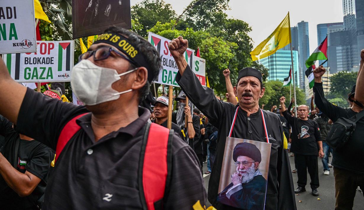 Aksi tersebut menjadi bentuk dukungan terhadap perjuangan rakyat Palestina di Gaza. Tampak dalam foto, seorang pria memegang plakat bergambar pemimpin tertinggi Iran, Ayatollah Ali Khamenei yang gugur dalam serangan Amerika Serikat dan Israel pada akhir Februari lalu, selama berunjuk rasa memperingati Hari Al-Quds, di Surabaya, Jawa Timur, Jumat (13/3/2026). (Juni KRISWANTO/AFP)