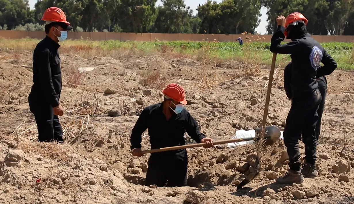 Gambar dari video pada 14 Juli 2019, pekerja Dewan Sipil Raqqa menggali kuburan massal berisi tulang belulang manusia di Raqqa, Suriah, 14 Juli 2019. Sejauh ini para pekerja telah menemukan 313 mayat dari kuburan massal yang ditemukan bulan lalu di dekat kota di Suriah utara tersebut. (AP Photo)