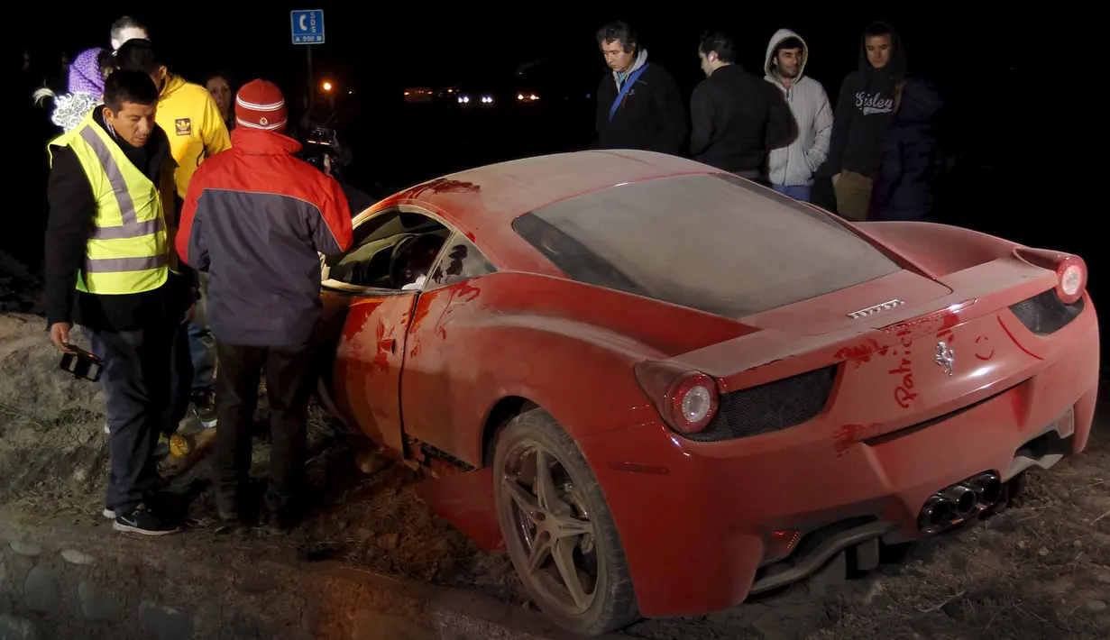 Sejumlah warga melihat kondisi mobil ferrari milik Arturo Vidal yang rusak parah usai mengalami kecelakaan di Kota Buin, Chile, Selasa (16/6/2015). Arturo Vidal mengalami luka ringan dan langsung dibawa ke rumah sakit. (REUTERS/Felipe Fredes)
