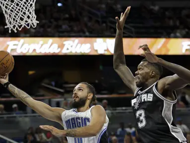 Pemain Orlando Magic, Evan Fournier (kiri) melakukan lay up saat dihadang pemain San Antonio Spurs, Dewayne Dedmon #3 pada laga NBA preseason basketball di Orlando. (AP/John Raoux)
