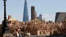 Pejalan kaki melintas di dekat patung skyline Kota London sepanjang 120 meter di London, Inggris, (30/8). Patung ini akan dibakar dalam sebuah acara untuk mengenang bencana Kebakaran besar London pada 1666. (REUTERS/Peter Nicholls)