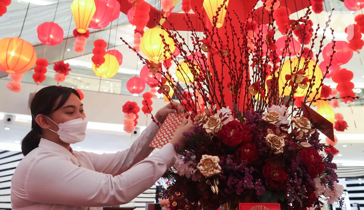 Seorang wanita menaruh amplop di Instalasi Red Lunar di Mal Senayan City, Jakarta, Kamis (19/1/2023). Instalasi tersebut bernuansa merah dan sentuhan emas, yang berisi Mei Hwa forest hingga Lantern towers dengan ratusan juntaian lampion indah. (Liputan6.com/Herman Zakharia)