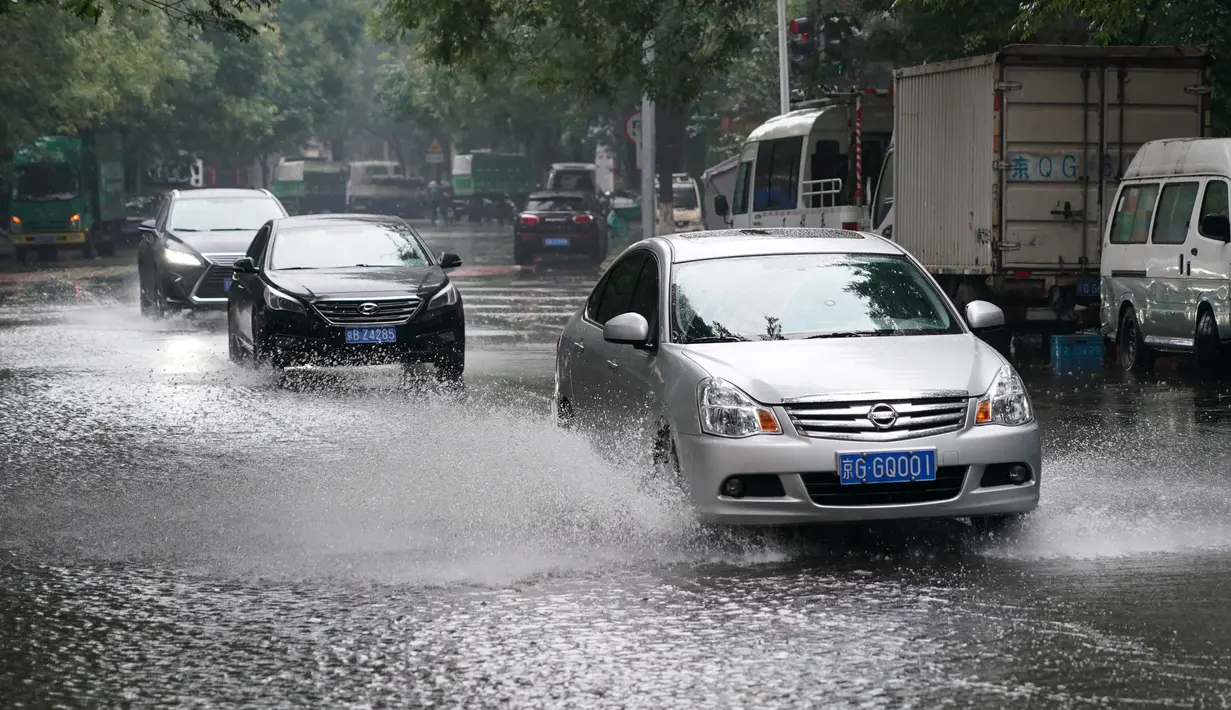 Mobil-mobil melintas di sebuah jalan yang tergenang air di Distrik Xicheng, Beijing, ibu kota China (12/8/2020). Badan meteorologi Beijing mengeluarkan peringatan siaga kuning untuk hujan badai. (Xinhua/Ju Huanzong)