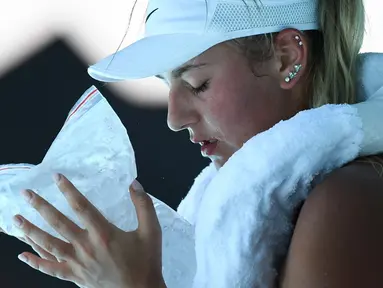 Petenis Ukraina Marta Kostyuk mendinginkan diri menggunakan kompres es saat bermain melawan petenis Spanyol Paula Badosa pada pertandingan tunggal putri turnamen tenis Australian Open di Melbourne, Australia, 21 Januari 2022. (William WEST/AFP)