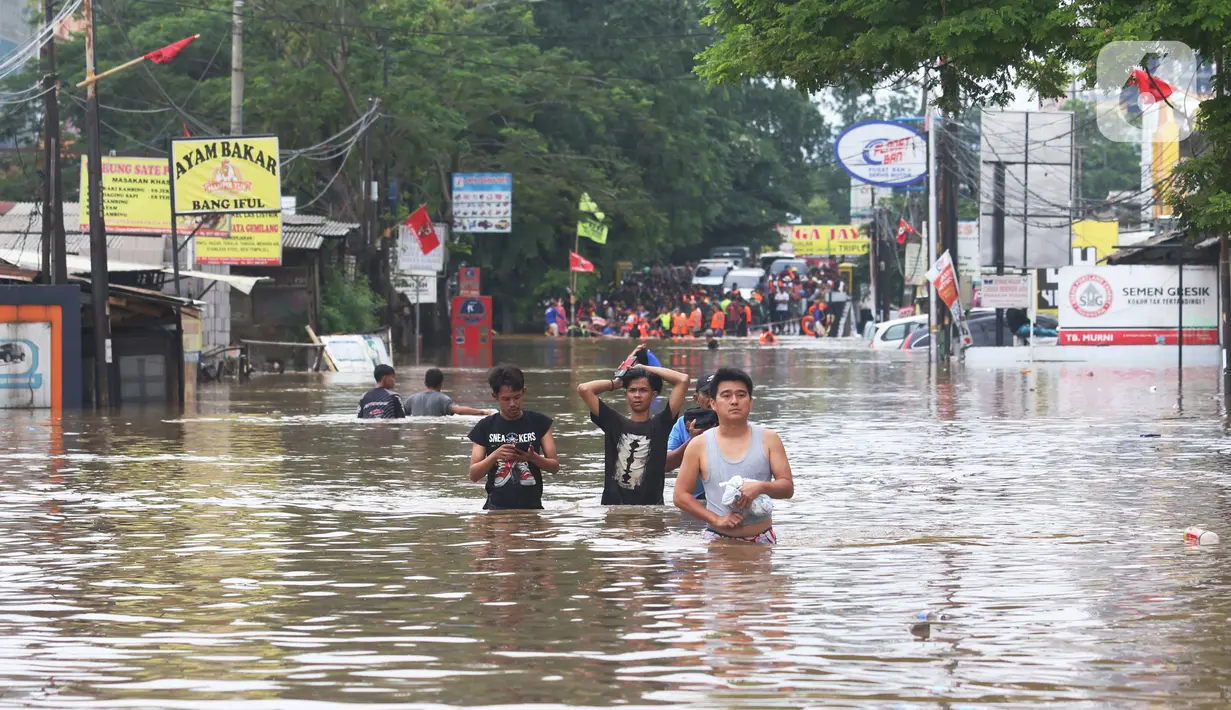Warga melintasi banjir  yang merendam jalan Raya KH Hasyim Ashari, Ciledug ,Tangerang, Rabu (1/1/2020). Banjir setinggi dada orang dewasa membuat jalur penghubung Tangerang ke Jakarta tersebut terputus tidak dapat dilintasi. (Liputan6.com/Angga Yuniar)