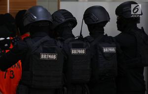 Polisi bersenjata lengkap mengawal sejumlah terduga teroris untuk dihadirkan dalam jumpa pers di Mabes Polri, Jakarta, Jumat (17/5/2019). Sepanjang bulan Mei 2019, tim Densus 88 Antiteror telah menangkap sebanyak 29 terduga teroris jaringan Jamaah Ansharut Daulah (JAD). (Liputan6.com/Johan Tallo)