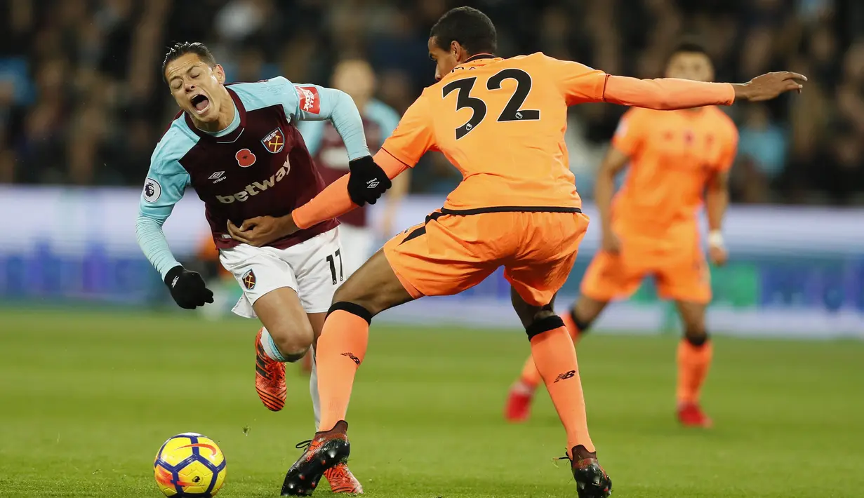 Pemain West Ham, Javier Hernandez (kiri) terjatuh saat akan melewati aadangan pemain Liverpool, Joel Matip pada lanjutan Premier League di London Stadium, London, (4/11/2017). Liverpool menang 4-1. (AP/Kirsty Wigglesworth)