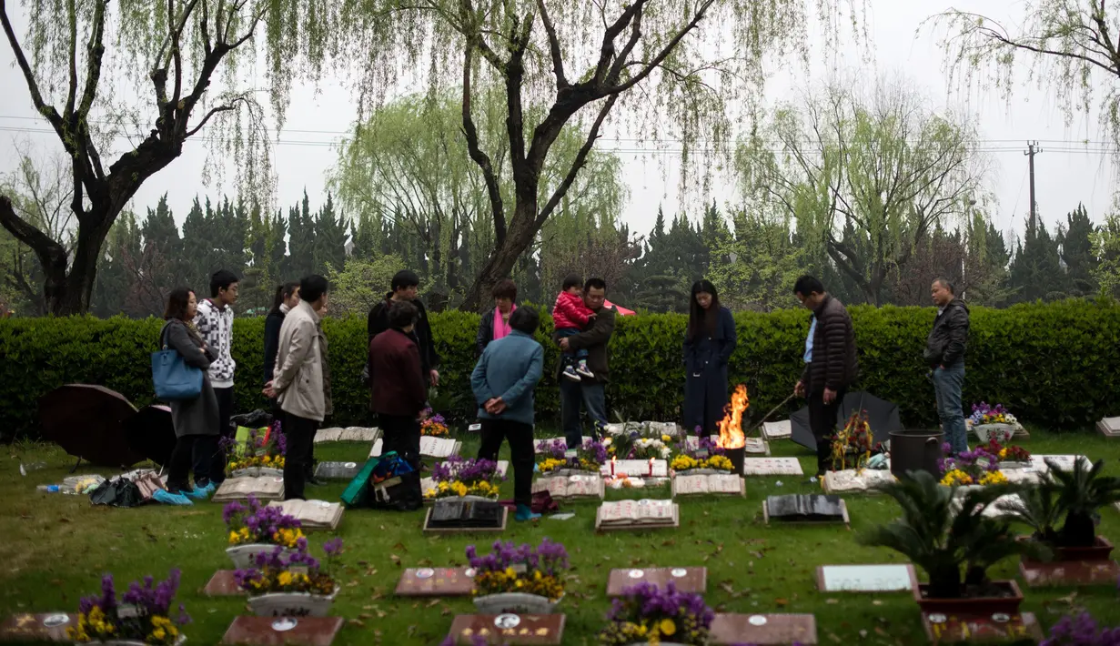 Sebuah keluarga membakar dupa saat mengunjungi pemakaman pada festival tahunan Qingming (Cheng Beng) di Shanghai, Minggu (3/4). Festival ini merupakan hari ziarah kubur ditandai dengan mengunjungi dan membersihkan kuburan leluhur. (Johannes EISELE/AFP)