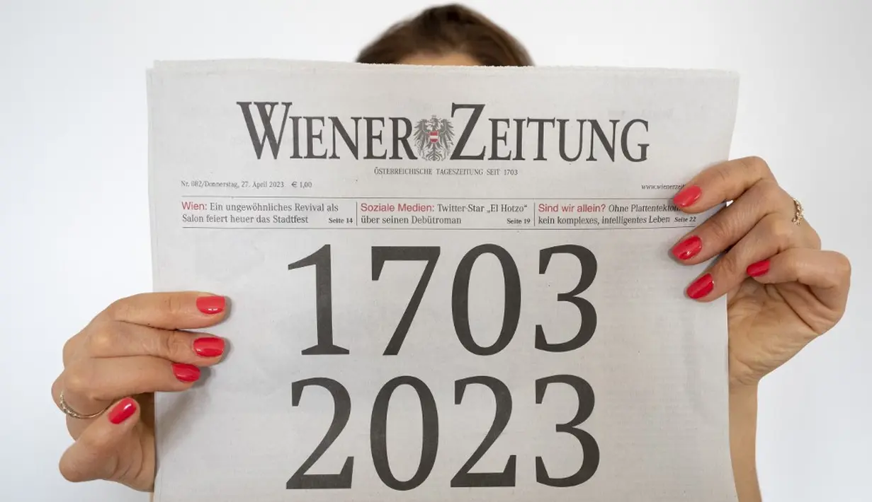 <p>Seorang wanita memegang koran "Wiener Zeitung" terbitan 27 April 2023 dengan halaman depan yang menggambarkan usia surat kabar tersebut selama 320 tahun di Wina, Austria, 27 April 2023. Wiener Zeitung adalah salah satu surat kabar tertua di dunia. (JOE KLAMAR/AFP)</p>