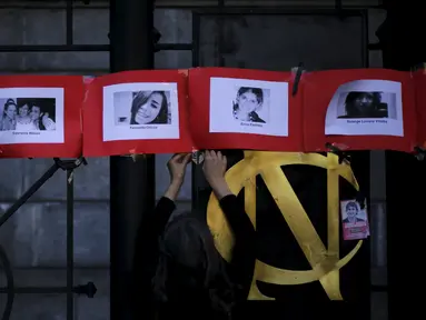 Seorang wanita menggantung foto korban kekerasan dalam rumah tangga saat memperingati Hari Internasional untuk Penghapusan Kekerasan terhadap Perempuan di Buenos Aires, Argentina, Rabu (25/11). (REUTERS/Marcos Brindicci)