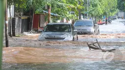 Hujan yang mengguyur Jakarta sejak Minggu (8/2) lalu, membuat Waduk Ria Rio meluap. Tampak 2 buah kendaraan menerobos banjir di kawasan Perumahan Pulomas, Jakarta, Selasa (10/2/2015). (Liputan6.com/Herman Zakharia)