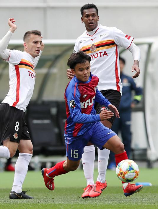 Gelandang Jepang Takefusa Kubo menggiring bola usai melewati dua pemain Nagoya Grampus Eight di Tokyo (13/3/2019). Kubo sempat mengenyam pendidikan di akademi Barcelona pada 2011 hingga 2015 silam. (AFP Photo/Jiji Press)