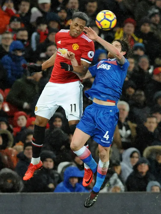Pemain Manchester United, Anthony Martial melompat untuk berebut bola dengan pemain Stoke City, Joe Allen pada laga pekan ke-23 Premier League 2017-2018 di Old Trafford, Senin (15/1). Manchester United mencetak tiga gol tanpa balas. (AP/Rui Vieira)