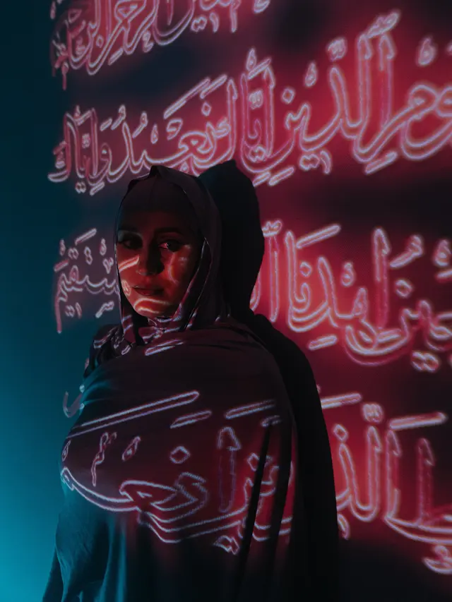 Wallpaper kaligrafi indah berupa foto muslimah dengan bayangan tulisan Arab
