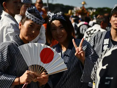 Dua wanita berpose saat mengikuti perayaan nasional untuk menandai penobatan Kaisar Jepang Naruhito di depan Istana Kekaisaran di Tokyo (9/11/2019). Kaisar Naruhito menjalankan ritual penobatannya setelah dilantik pada 1 Mei 2019. (AFP Photo/Charly Triballeau)