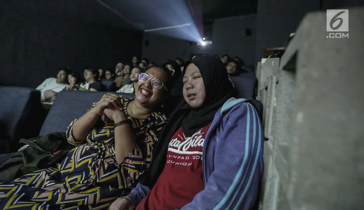Sejumlah penyandang tunanetra mendengarkan relawan bisik saat menyaksikan film di Bioskop Bisik di Pavilliun 28, Jakarta, Minggu (14/1).  Kini, menonton bioskop bukan menjadi hal mustahil lagi bagi penyandang tunanetra. (Liputan6.com/Faizal Fanani)