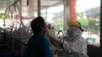 Paramedis melakukan pengambilan sampel spesimen terhadap salah seorang warga yang beraktivitas di Pasar Raya.