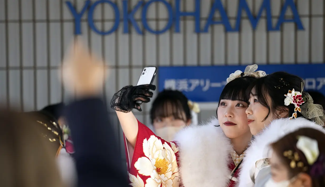 Perempuan Jepang berkimono yang merayakan ulang tahun ke-20 berswafoto sebelum berpartisipasi dalam upacara resmi, yang biasa disebut upacara Kedewasaan di Yokohama dekat Tokyo, Senin (9/1/2023). Jepang menurunkan usia dewasa dari 20 tahun menjadi 18 tahun pada 2022. (AP Photo/Eugene Hoshiko)