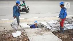 Petugas membersihkan saluran gorong-gorong air di Jalan DI Panjaitan, Kebon Nanas, Jakarta, Jumat (6/12/2019). Hal tersebut dilakukan guna mengantisipasi tersumbatnya saluran air selama memasuki periode musim hujan. (Liputan6.com/Immanuel Antonius)