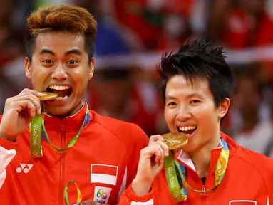 Pasangan ganda campuran Indonesia, Tontowi Ahmad dan Liliyana Natsir mengigit medali emas usai mengalahkan lawannya asal Malaysia Peng Soon Chan dan Liu Ying Goh pada final bulutangkis di Riocentro Pavilion 4 , Brasil. (REUTERS/Mike Blake)