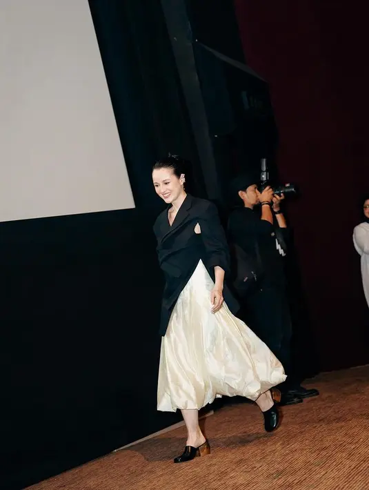 Julie memilih mengenakan atasan hitam lengan panjang dengan model blazer asimetris dari Tangan Official dipadukan rok panjang high waist satin warna kuning. [@julstelle]