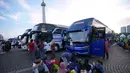 Sehari sebelumnya, Senin (16/3/2026), Pemprov DKI Jakarta telah melepas 388 unit sepeda motor milik pemudik dari Terminal Pulogadung menggunakan 15 truk agar dapat digunakan berlebaran di kampung halaman. Tampak dalam foto, orang-orang menunggu untuk menaiki bus yang akan mengangkut mereka ke kampung halaman untuk merayakan Hari Raya Idul Fitri 1447 Hijriah dalam perjalanan mudik gratis yang diselenggarakan oleh Pemerintah Provinsi Jakarta di Lapangan Monumen Nasional, Selasa 17 Maret 2026. (AP Photo/Achmad Ibrahim)