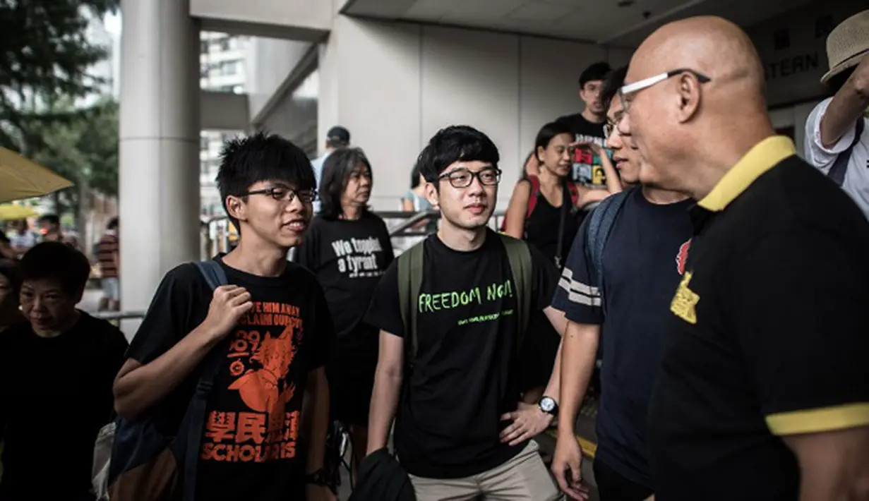 Joshua Wong (kiri) dan Nathan Law (tengah) berbincang dengan pendukungnya di luar pengadilan, Hong Kong, Cina, Jumat (28/8/2015). Nathan Law dan Joshua Wong berperan dalam aksi mahasiswa dan pelajar di Hong Kong 2014 lalu. (AFP PHOTO/Philippe Lopez)