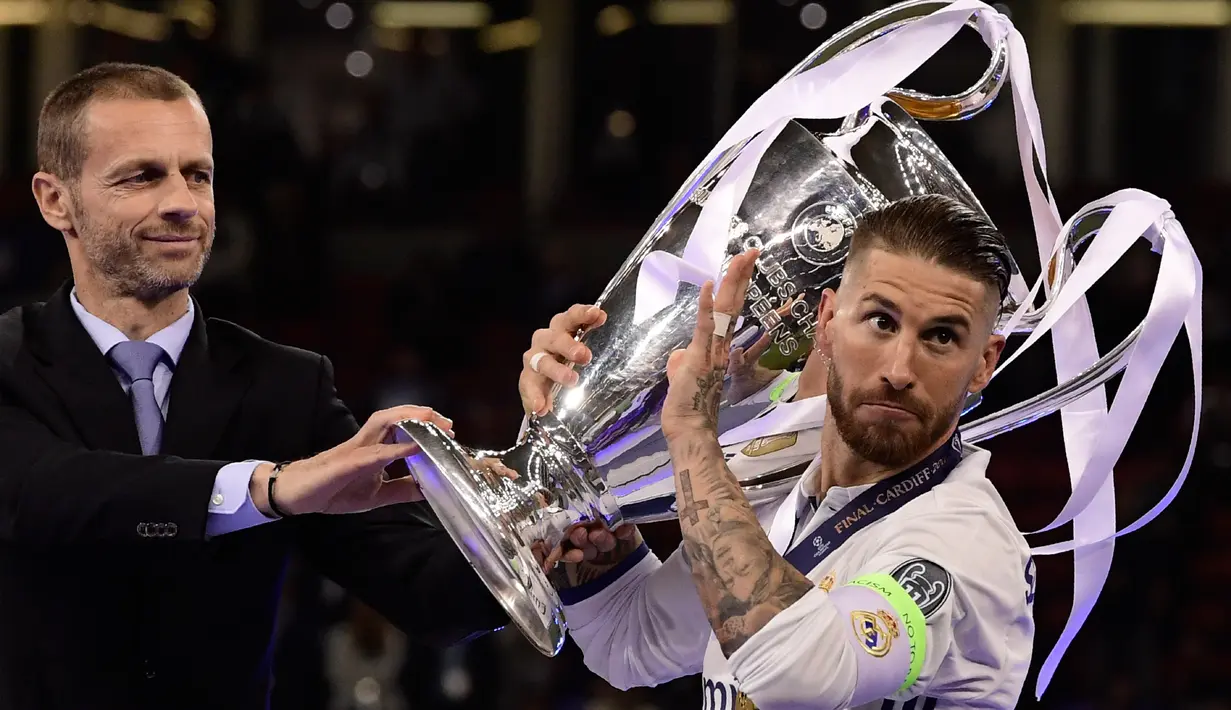 Presiden UEFA, Aleksander Ceferin memberikan piala kepada kapten Real Madrid, Sergio Ramos usai Real Madrid memenangkan pertandingan Liga Champions di Stadion Cardiff, Wales (3/6). (AFP Photo/Javier Soriano)