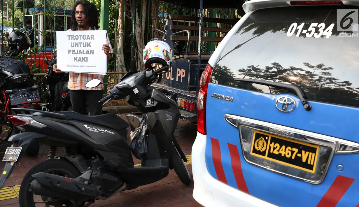 Aktivis Koalisi Pejalan Kaki (KPK) melakukan aksi di sepanjang trotoar kawasan Monas, Jakarta, Jumat (28/7). Dalam aksinya akitivis membawa poster yang mengimbau trotoar sebagai tempat bagi pejalan kaki. (Liputan6.com/Immanuel Antonius)
