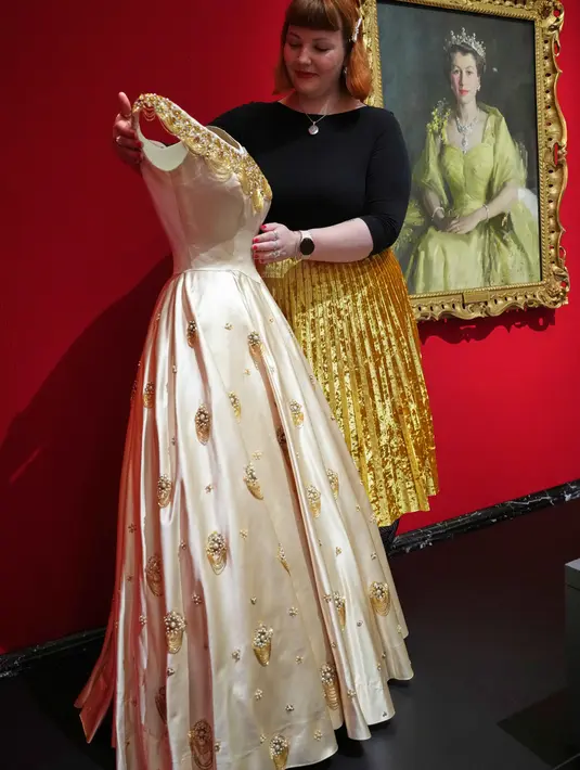 Pameran ini akan digelar di The King's Gallery, Istana Buckingham, London, Inggris, mulai dari 10 April hingga musim gugur 2026. Tampak dalam foto, seorang anggota staf Royal Collection Trust menyesuaikan gaun malam dari tahun 1952 yang dikenakan oleh Ratu Elizabeth II, yang dipamerkan di pameran 'Queen Elizabeth II: Her Life in Style', di The King's Gallery, Istana Buckingham, London, Inggris, Kamis 9 April 2026. (AP Photo/Kirsty Wigglesworth)