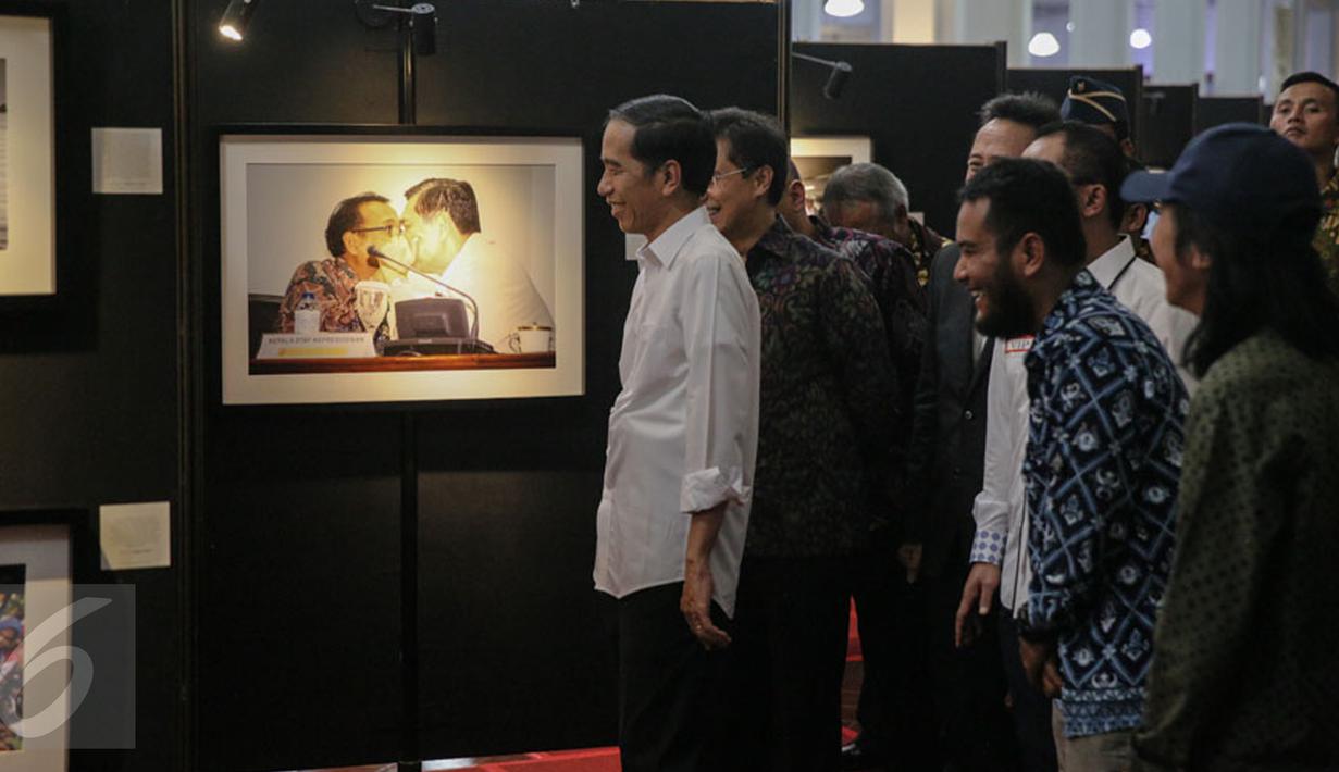 Presiden Joko Widodo melihat karya foto yang dipajang pada pameran foto jurnalistik Setahun Kerja Jokowi-JK di Museum Bank Mandiri, Jakarta, Jumat (18/12). Foto tersebut merupakan karya para anggota Pewarta Foto Indonesia (Liputan6.com/Faizal Fanani)