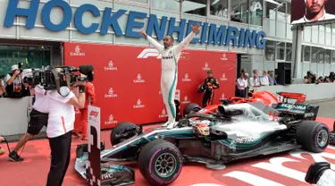 Pembalap Mercedes, Lewis Hamilton berselebrasi setelah berhasil finish pertama pada balapan F1 GP Jerman di Sirkuit Hockenheim, Minggu (22/7). Kemenangan ini diraih secara dramatis karena Hamilton mengawali balapan dari urutan ke-14. (AP/Jens Meyer)