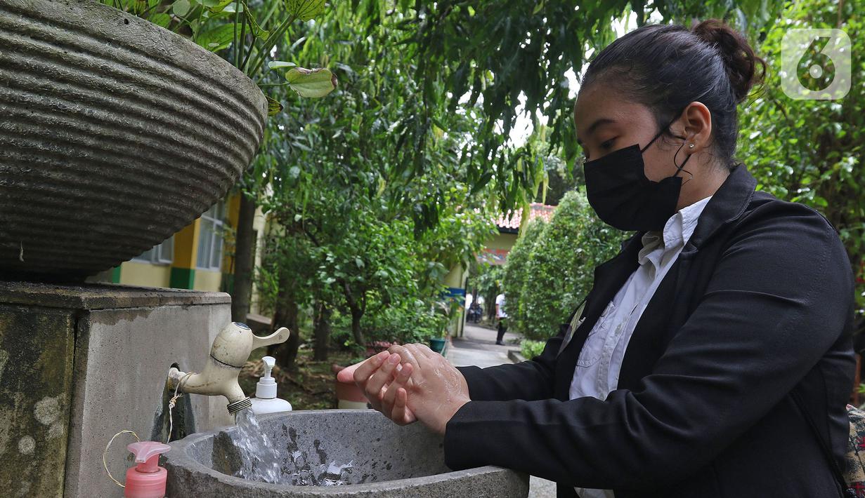 Murid sedang mencuci tangan saat tiba di sekolah  SMKN 51, Jakarta, Rabu (7/4/2021). Para murid diwajibakan membawa makanan sendiri  dan mengikuti syarat & panduan sekolah tatap muka seperti membuka pintu dan jendela.(Liputan6.com/Herman Zakharia)