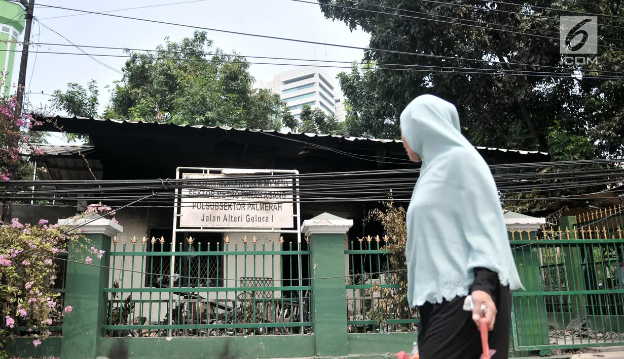 Warga melintas di depan pos polisi Subsektor Palmerah yang hangus dibakar demonstran, Jakarta, Rabu (25/9/2019). Aksi pembakaran oleh amukan demonstran tersebut menghanguskan hampir seluruh bagian gedung pos polisi, sepeda motor serta barang-barang di dalamnya. (merdeka.com/Iqbal S. Nugroho)