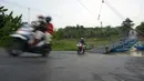 Pengendara sepeda motor melintasi jembatan perahu di atas Sungai Citarum, Karawang, Jawa Barat, Sabtu (20/11/2021). Tarif sekali melewati jembatan perahu ini dipatok Rp 2.000 per sepeda motor dan Rp 1.000 bagi pejalan kaki. (merdeka.com/Imam Buhori)